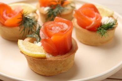 Photo of Tasty tartlets with salmon, lemon and dill on table, closeup