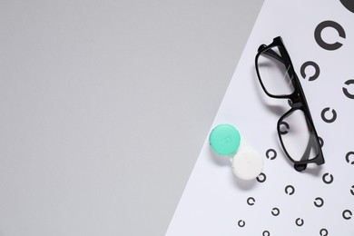 Photo of Glasses, vision test chart and lenses on gray background, flat lay. Space for text