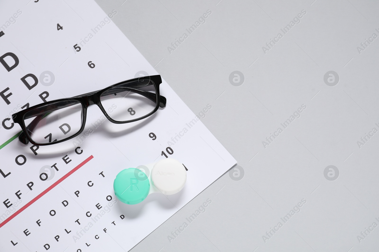 Photo of Glasses, vision test chart and lenses on gray background, flat lay. Space for text