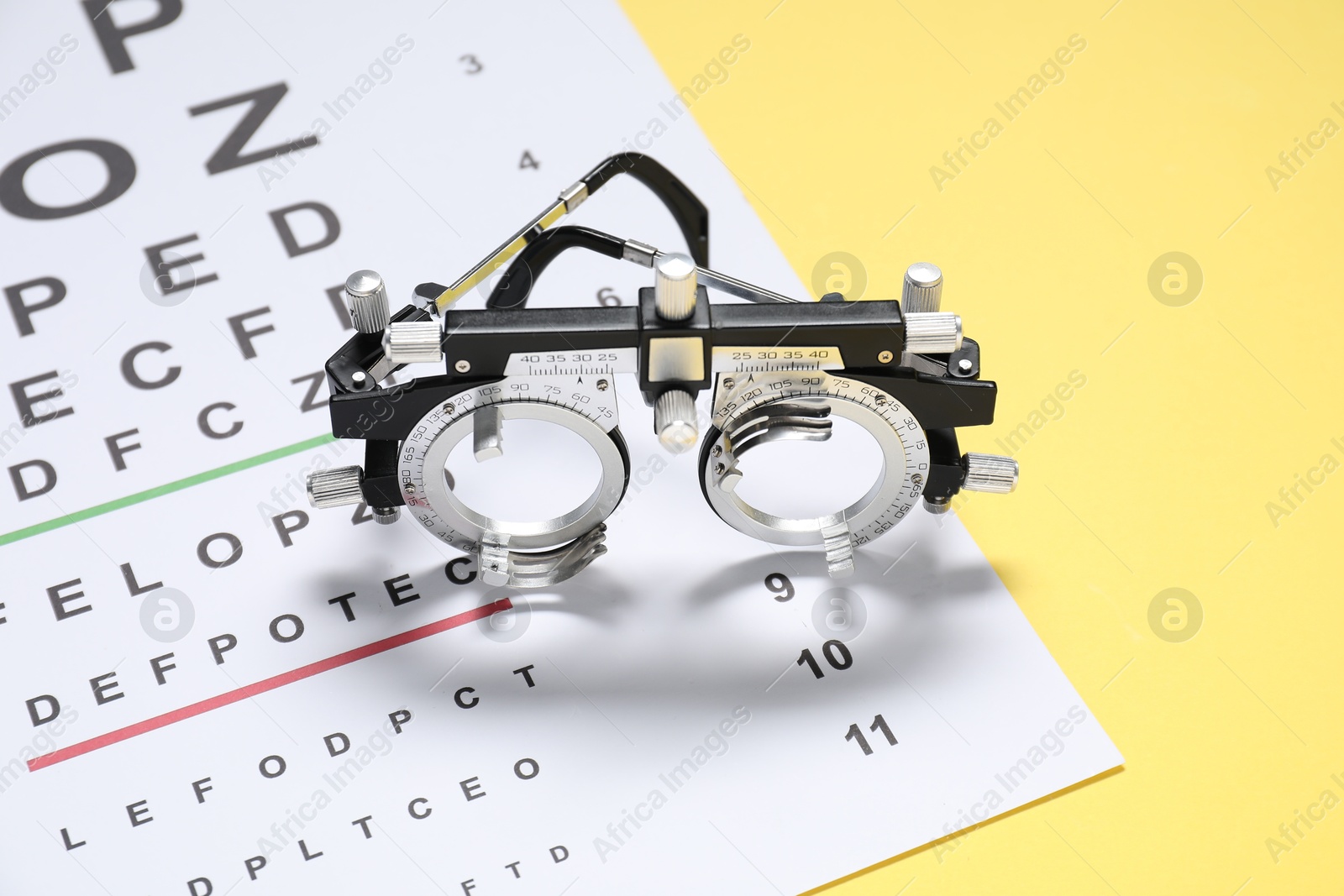 Photo of Vision test chart and trial frame on yellow background