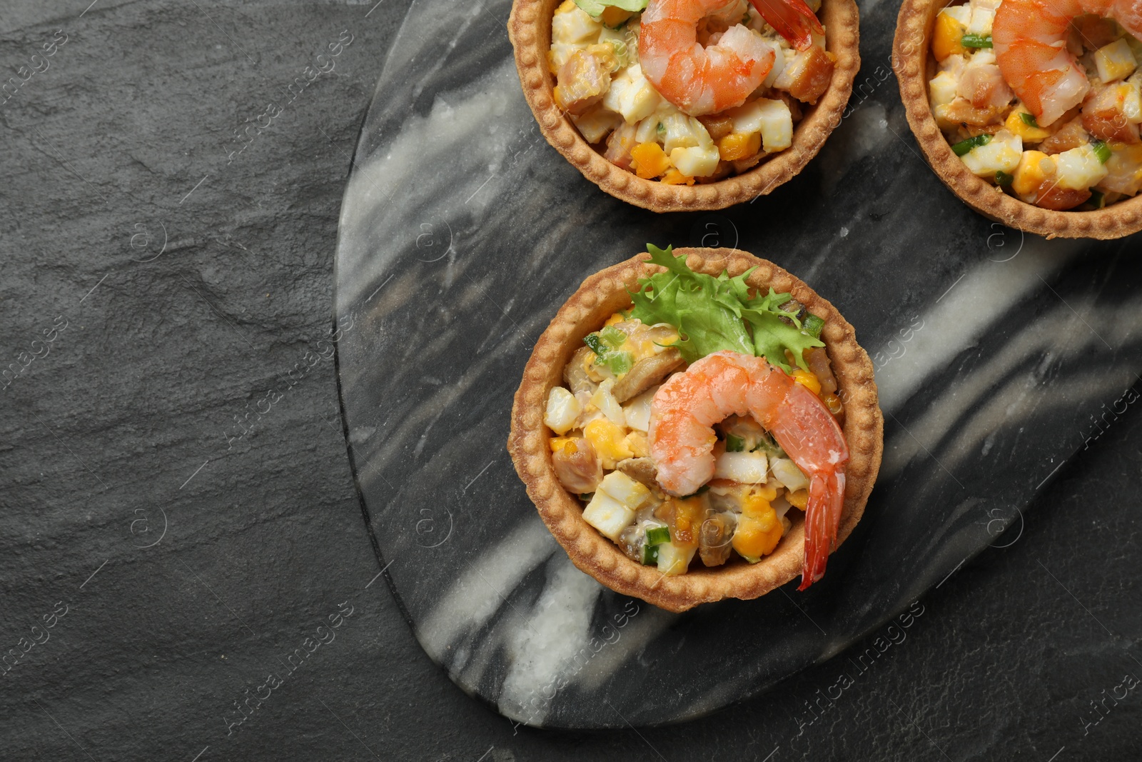 Photo of Tartlets with delicious filling on black table, top view. Space for text