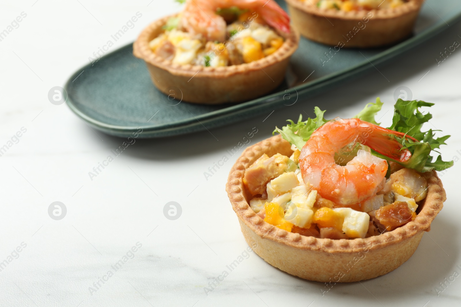 Photo of Tartlets with delicious filling on white marble table, closeup. Space for text