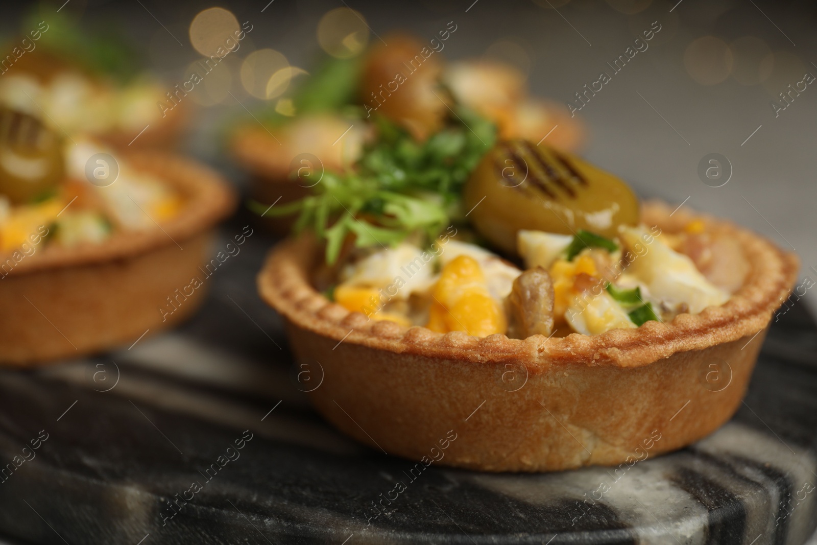 Photo of Tartlets with delicious filling on table, closeup. Bokeh effect