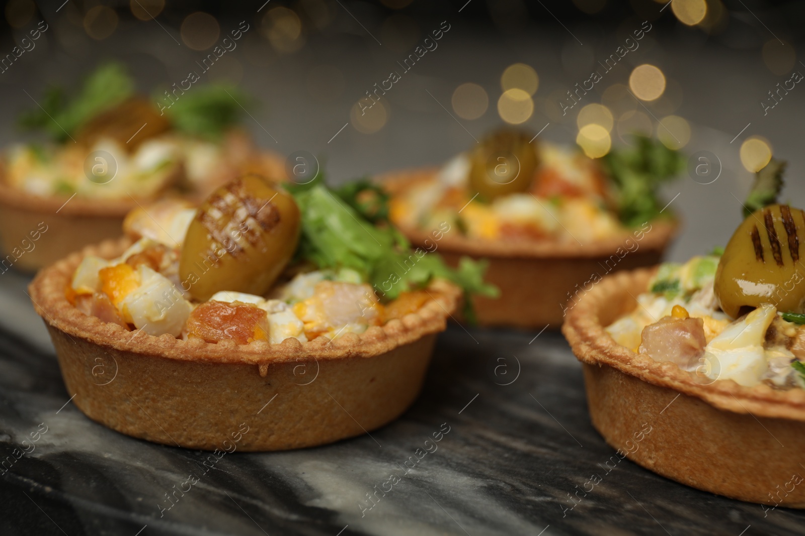 Photo of Tartlets with delicious filling on table, closeup. Bokeh effect