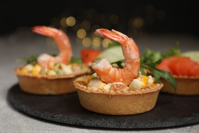 Photo of Tartlets with delicious fillings on grey table, closeup. Bokeh effect