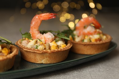 Photo of Tartlets with delicious filling on grey table, closeup. Bokeh effect