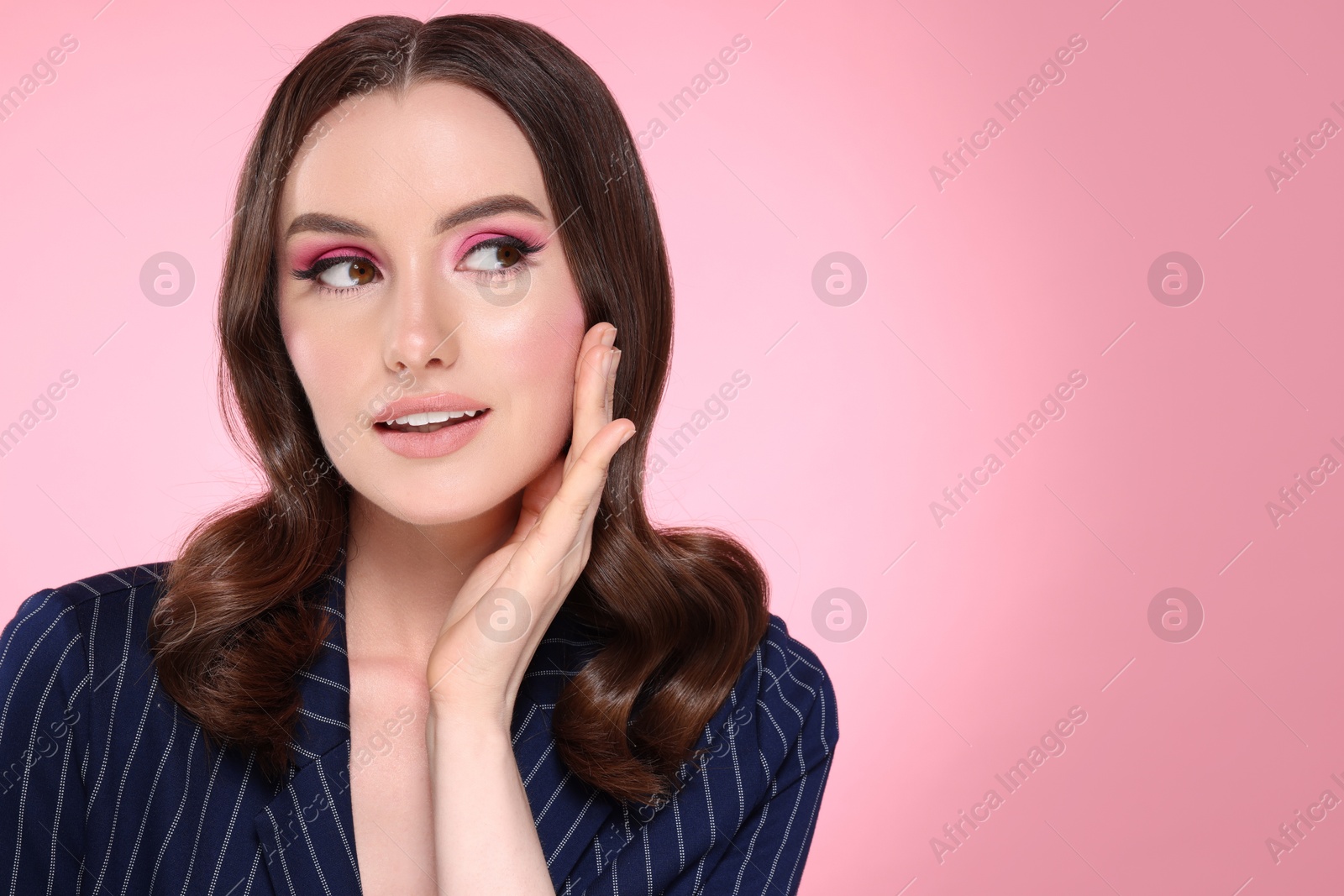 Photo of Portrait of beautiful young woman with stylish makeup and gorgeous hair on pink background. Space for text