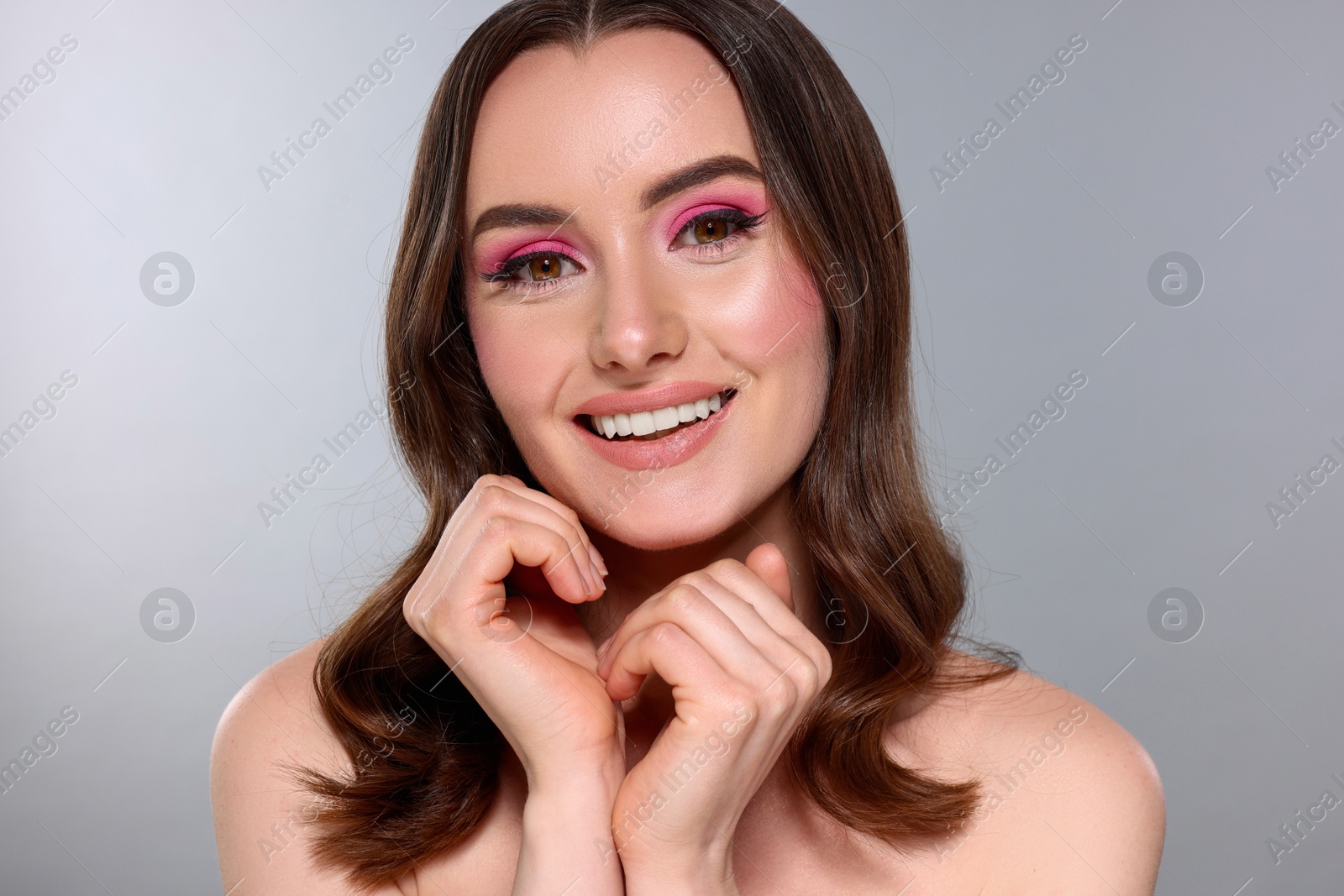 Photo of Portrait of beautiful young woman with stylish makeup and gorgeous hair on light grey background