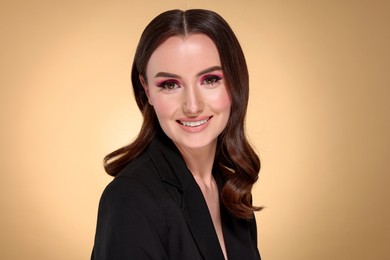 Photo of Portrait of beautiful young woman with stylish makeup and gorgeous hair on beige background