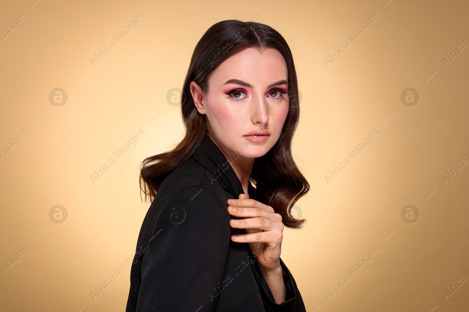 Photo of Portrait of beautiful young woman with stylish makeup and gorgeous hair on beige background