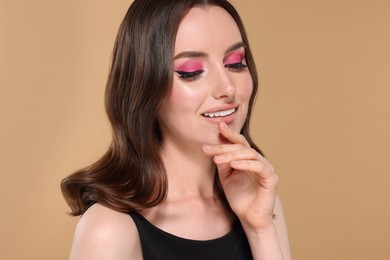 Photo of Portrait of beautiful young woman with stylish makeup and gorgeous hair on beige background