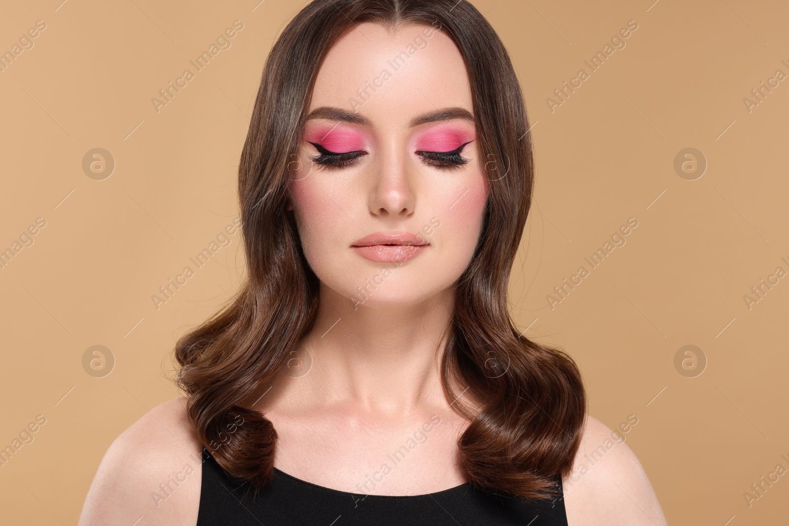 Photo of Portrait of beautiful young woman with stylish makeup and gorgeous hair on beige background