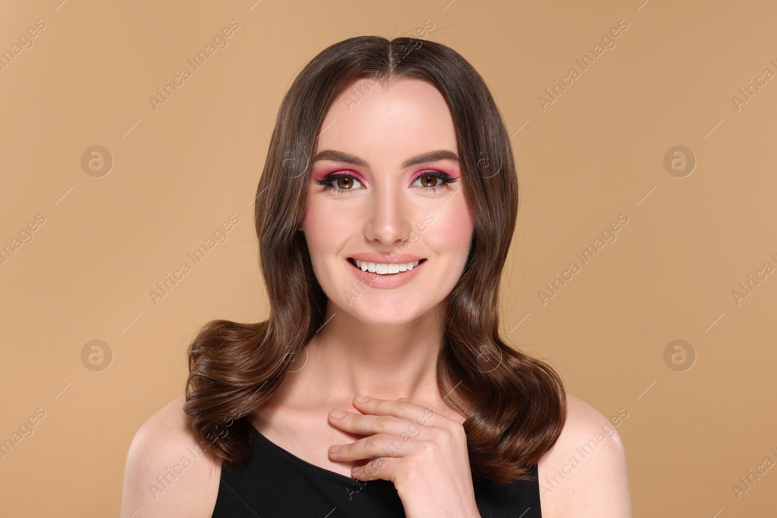 Photo of Portrait of beautiful young woman with stylish makeup and gorgeous hair on beige background