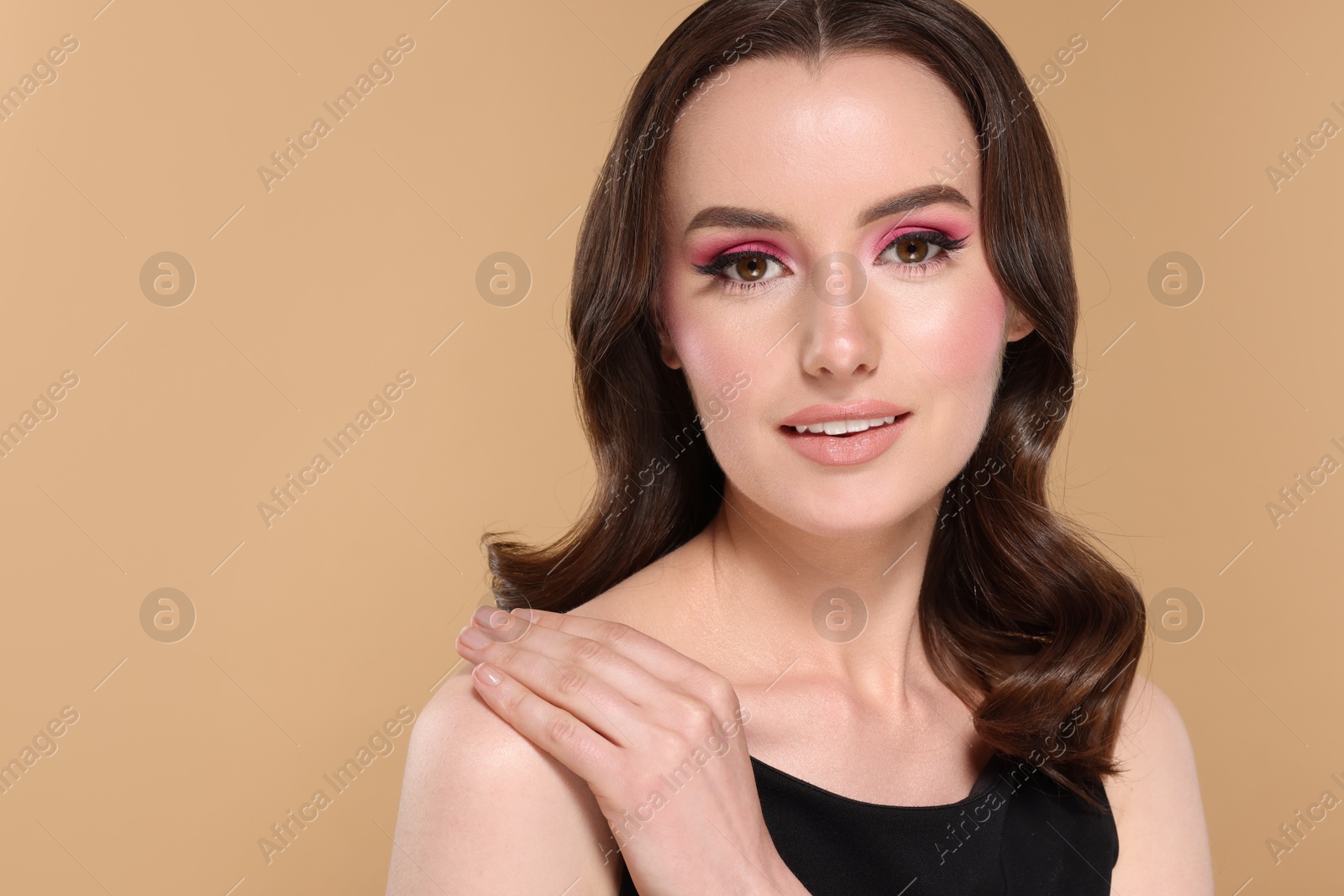 Photo of Portrait of beautiful young woman with stylish makeup and gorgeous hair on beige background. Space for text