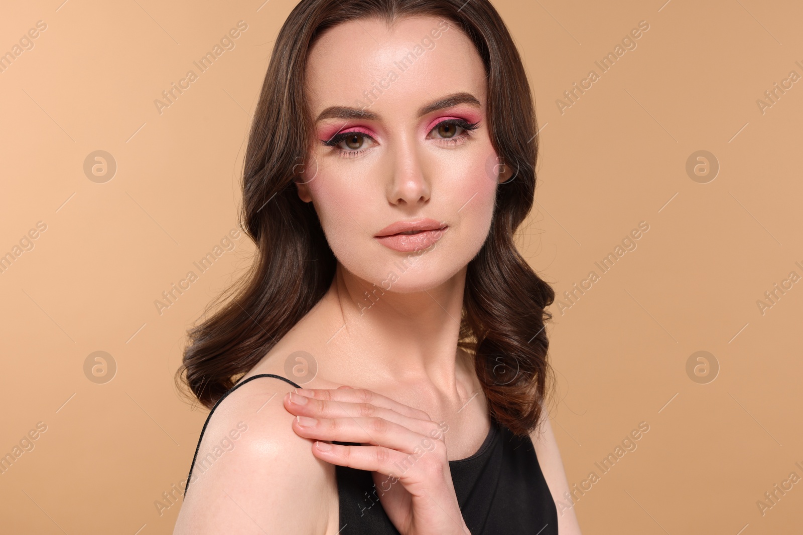 Photo of Portrait of beautiful young woman with stylish makeup and gorgeous hair on beige background