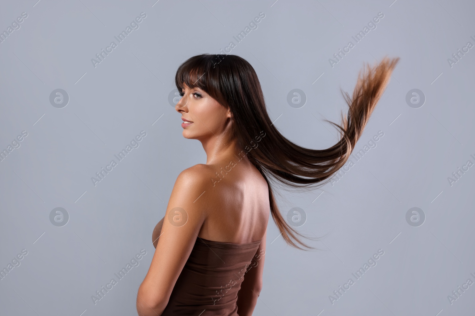 Photo of Hair styling. Beautiful woman with straight long hair on grey background