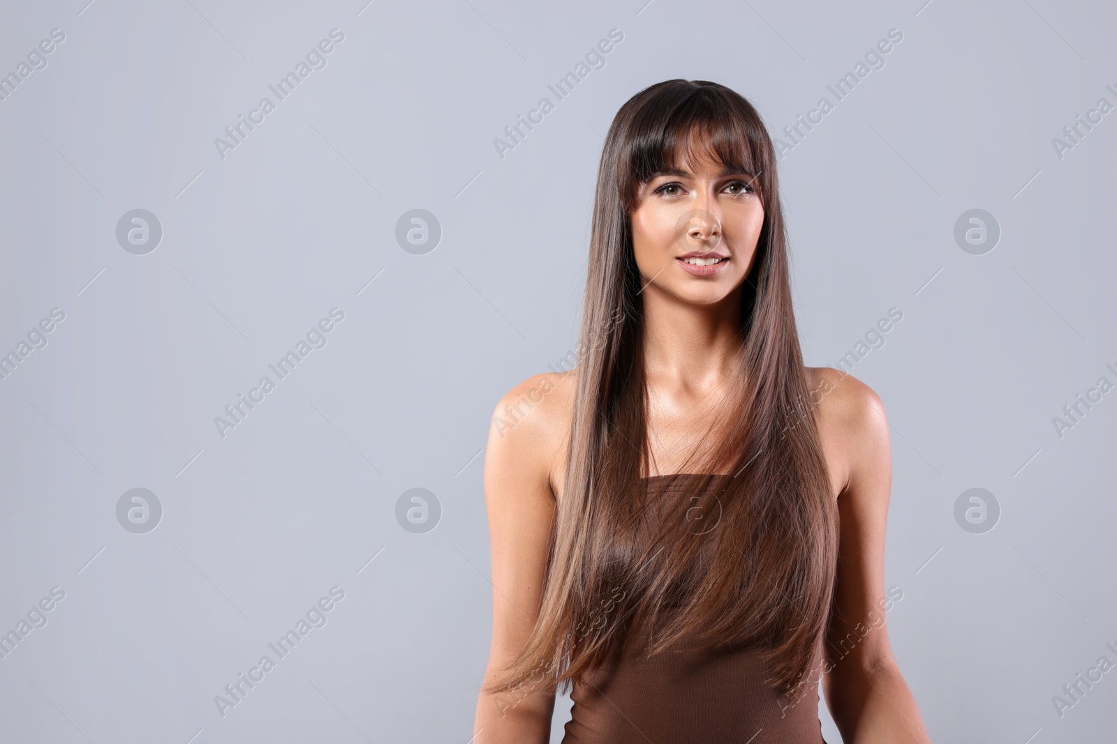 Photo of Hair styling. Portrait of beautiful woman with straight long hair on grey background, space for text