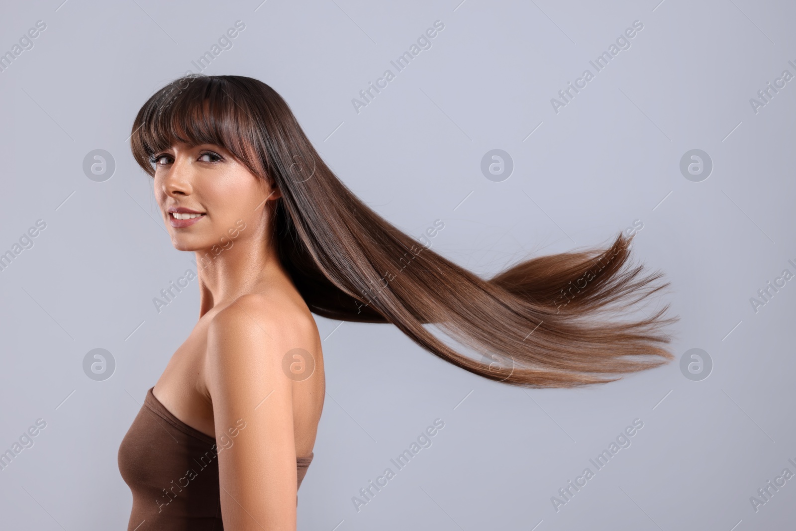 Photo of Hair styling. Portrait of beautiful woman with straight long hair on grey background, space for text