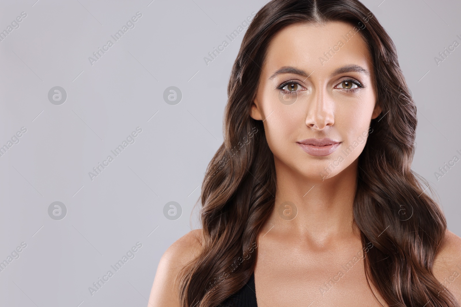 Photo of Hair styling. Portrait of beautiful woman with wavy long hair on grey background, space for text