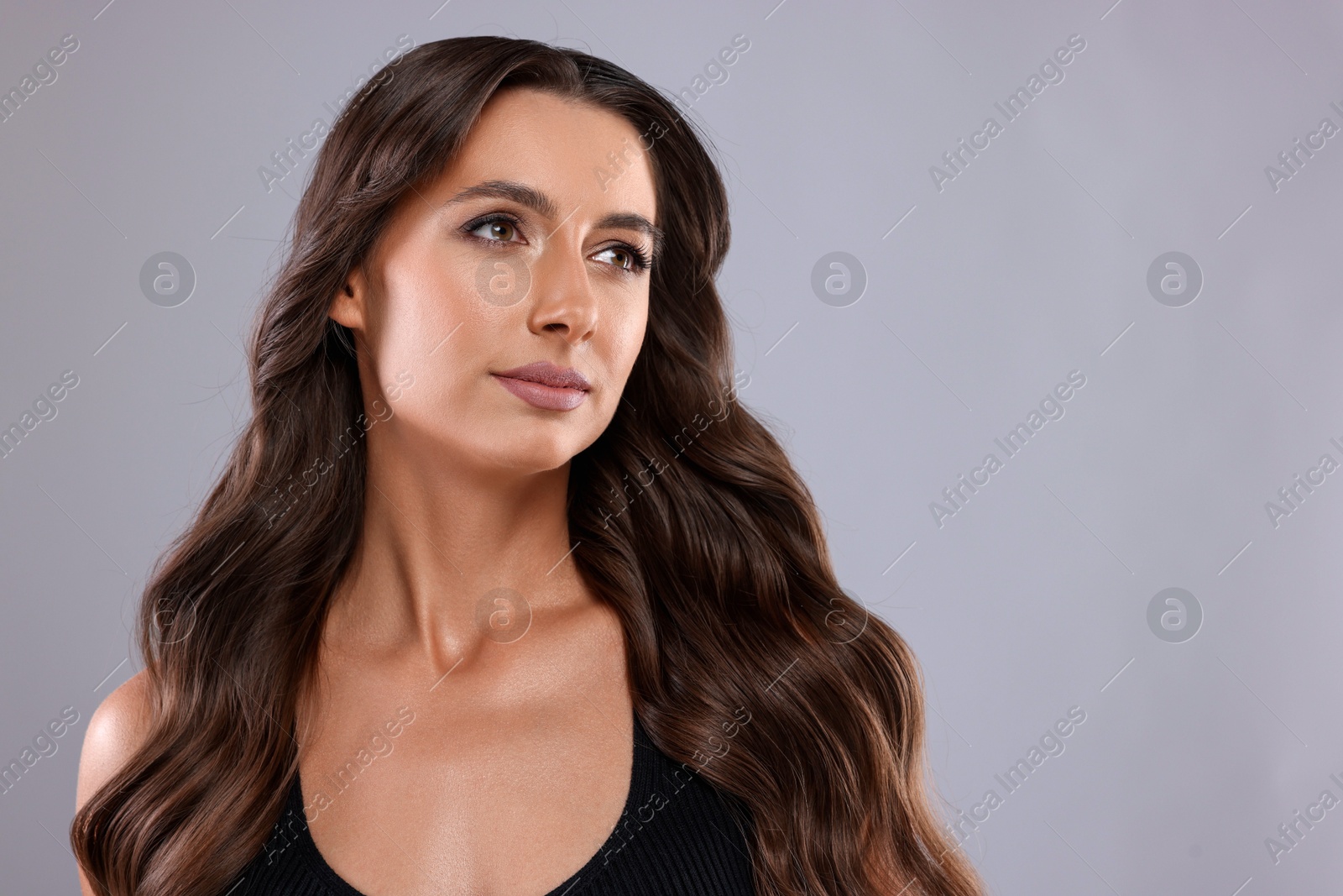 Photo of Hair styling. Beautiful woman with wavy long hair on grey background, space for text