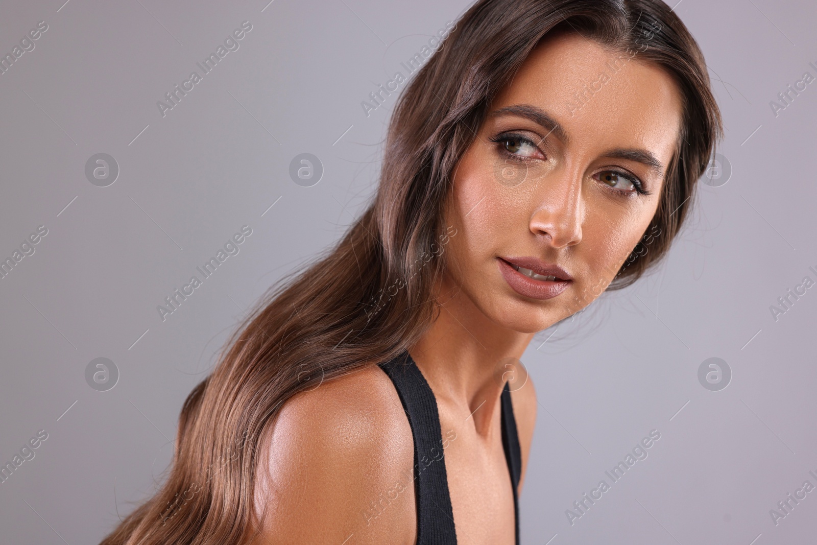 Photo of Hair styling. Beautiful woman with wavy long hair on grey background, closeup