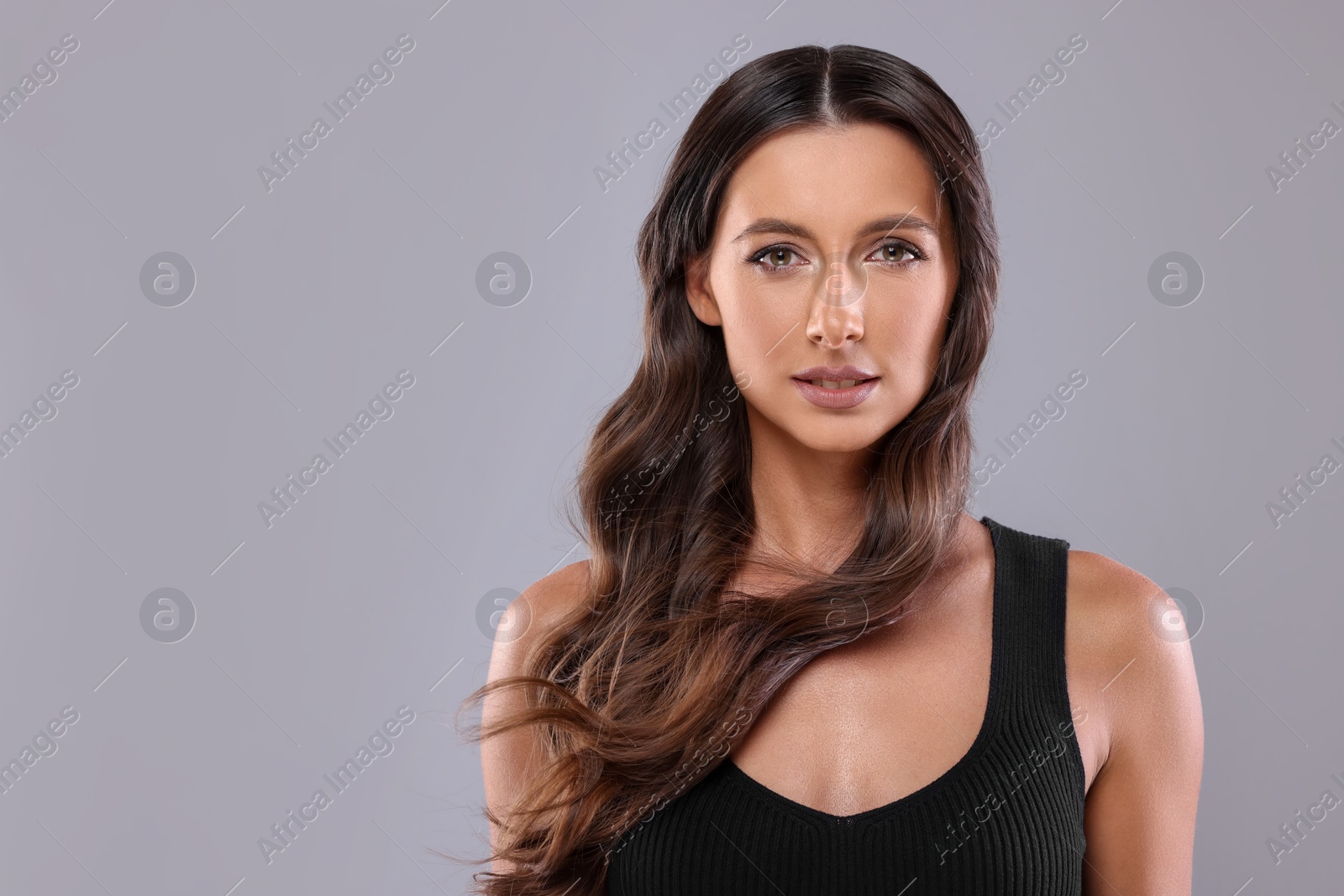 Photo of Hair styling. Portrait of beautiful woman with wavy long hair on grey background, space for text