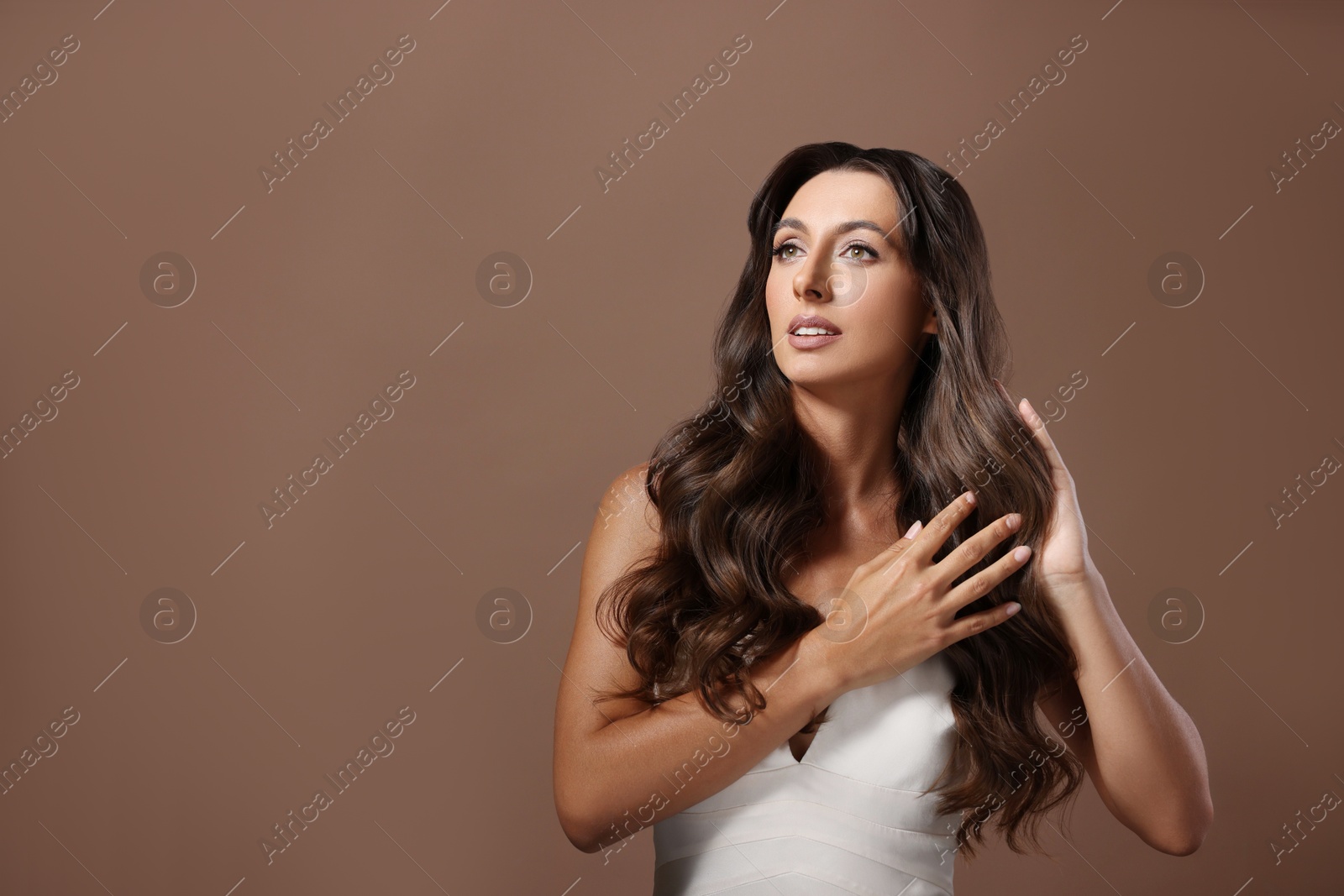 Photo of Hair styling. Beautiful woman with wavy long hair on brown background, space for text