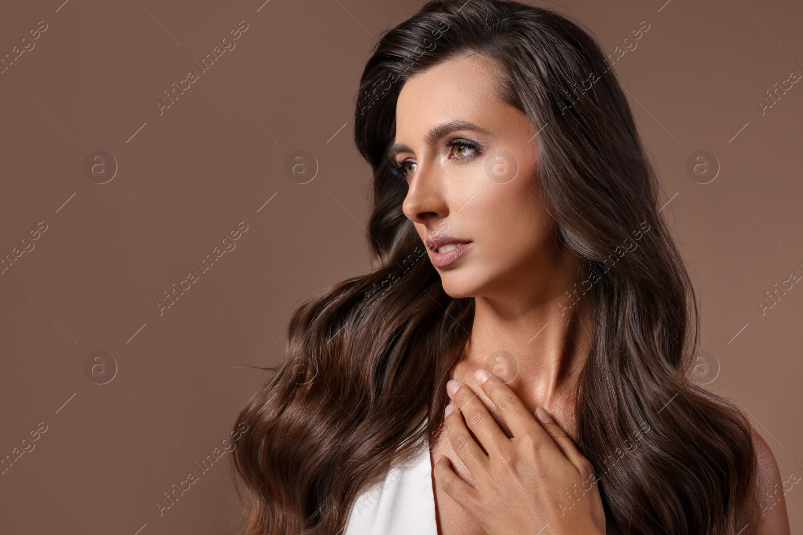 Photo of Hair styling. Beautiful woman with wavy long hair on brown background, space for text