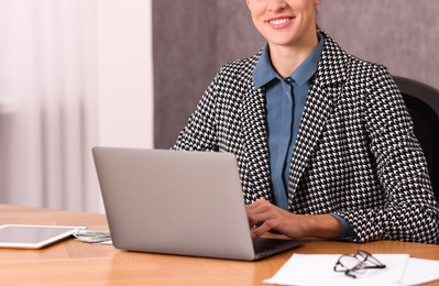 Photo of Banker working with laptop at wooden table in office