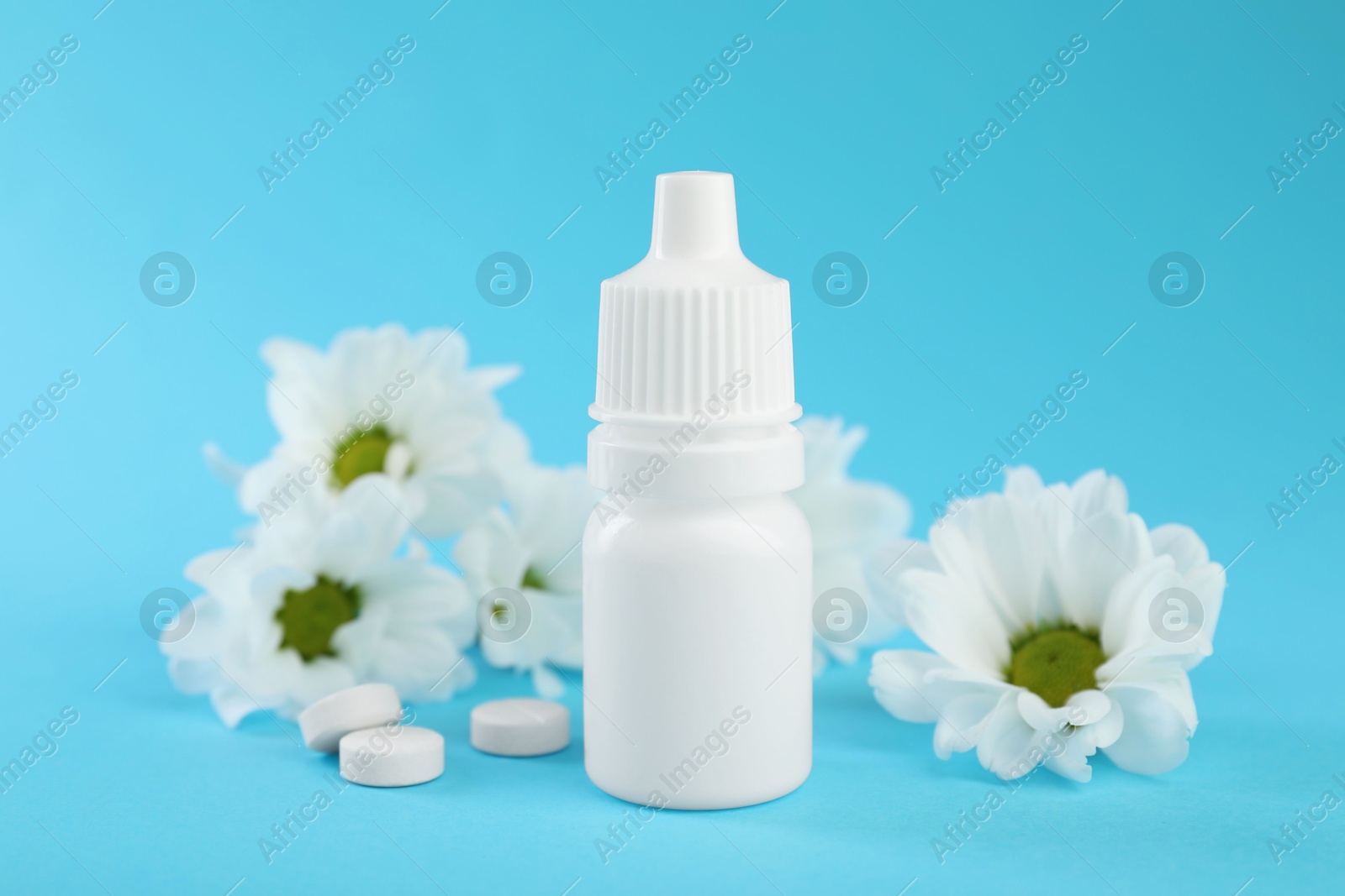 Photo of Allergy treatment. Nasal drops, pills and flowers on light blue background, closeup