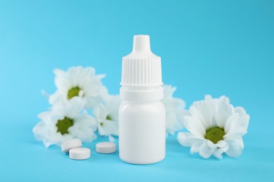 Photo of Allergy treatment. Nasal drops, pills and flowers on light blue background, closeup