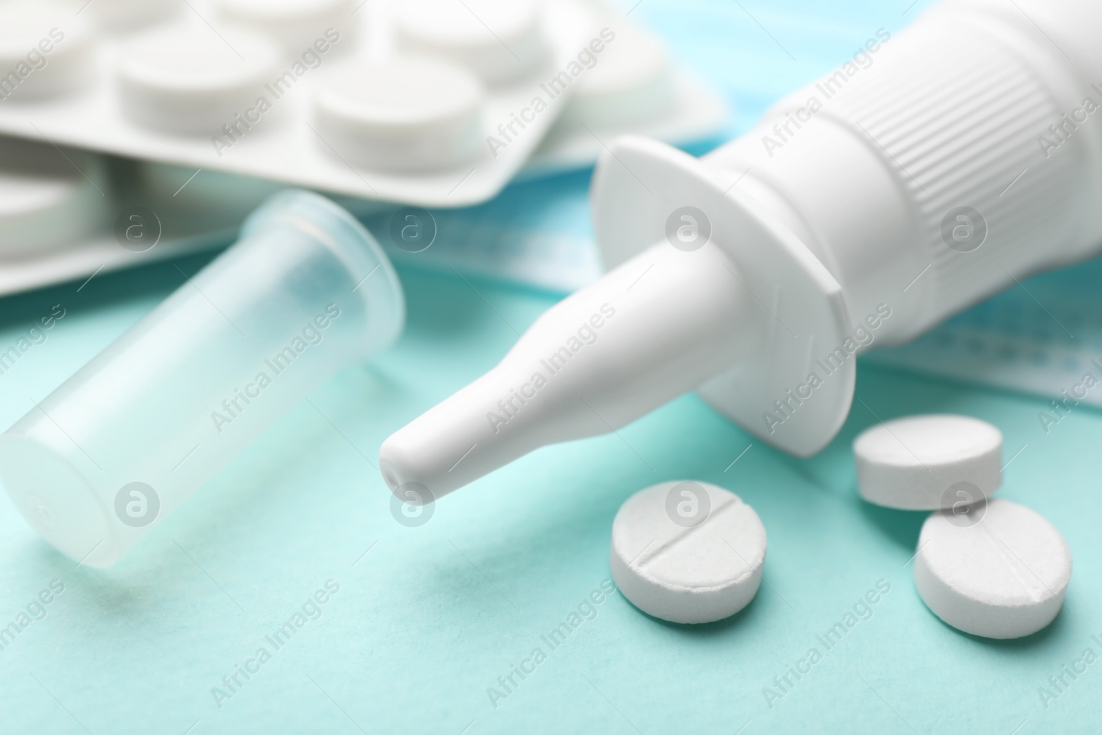 Photo of Allergy treatment. Nasal spray and pills on light blue background, closeup