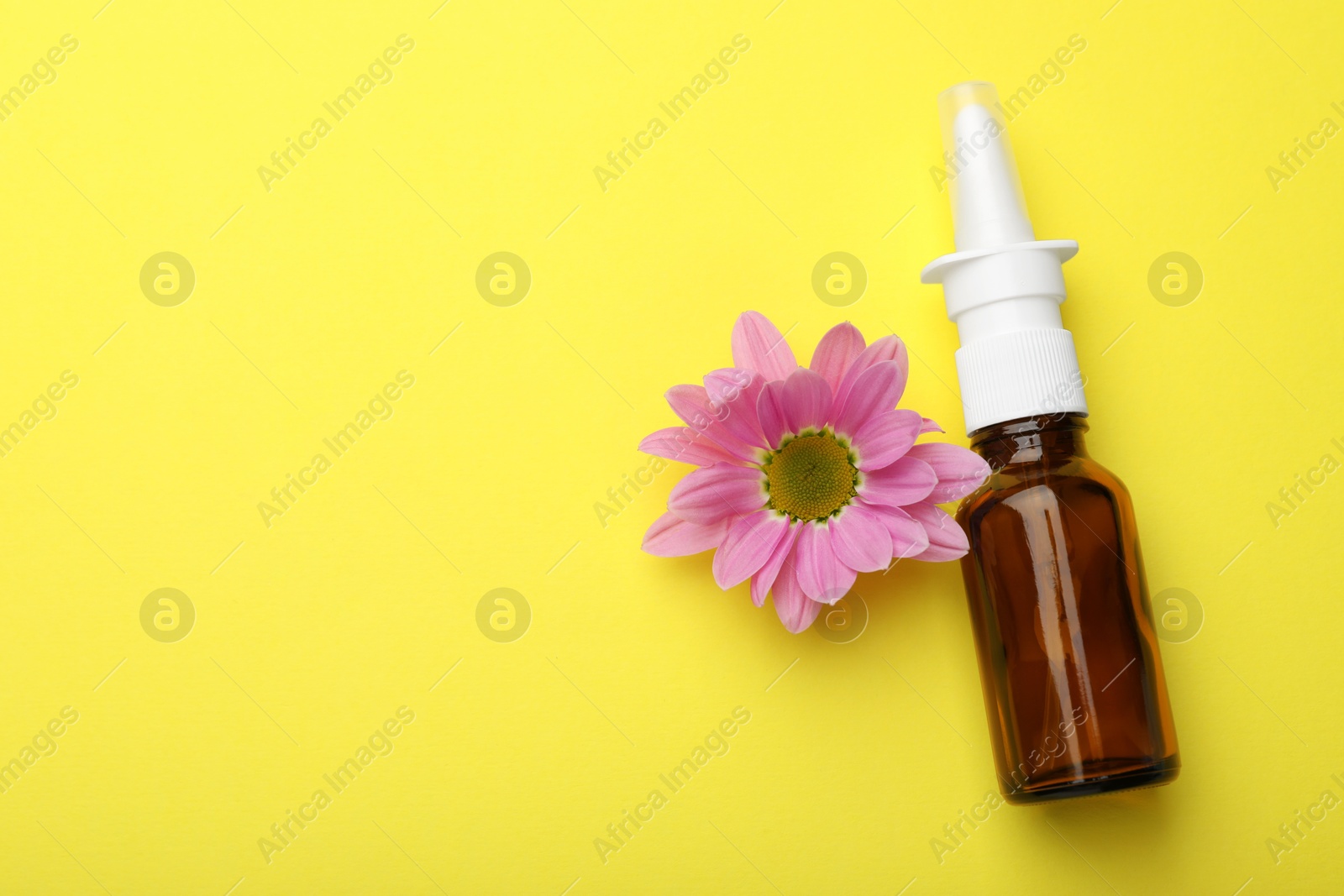 Photo of Allergy treatment. Nasal spray and flower on yellow background, top view. Space for text