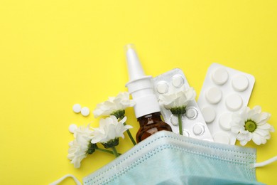 Photo of Allergy treatment. Nasal spray, pills, protective mask and flowers on yellow background, flat lay