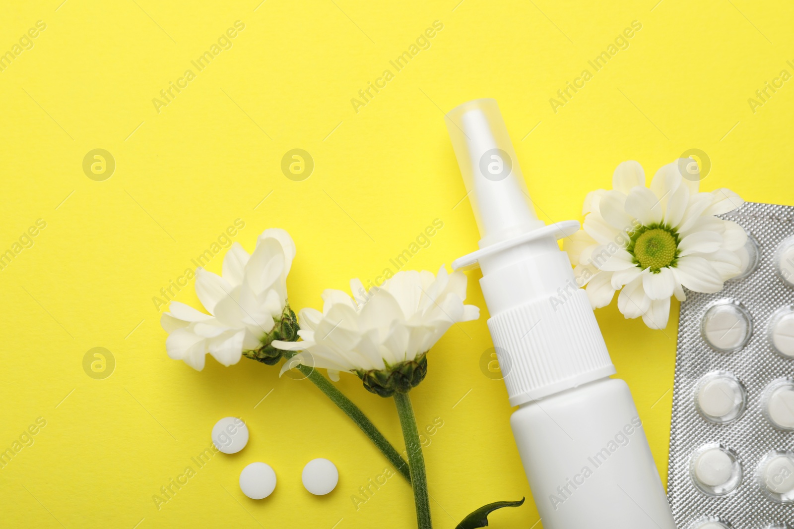 Photo of Allergy treatment. Nasal spray, pills and flowers on yellow background, flat lay. Space for text