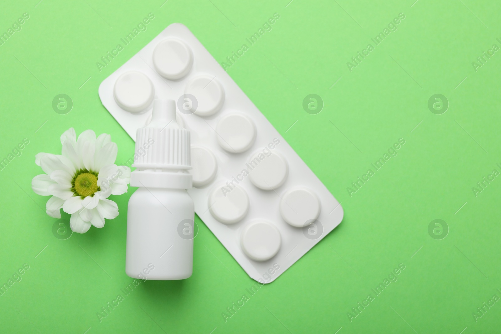 Photo of Allergy treatment. Nasal drops, pills and flower on green background, flat lay. Space for text