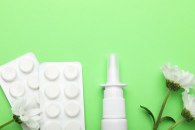 Photo of Allergy treatment. Nasal spray, pills and flowers on green background, flat lay. Space for text