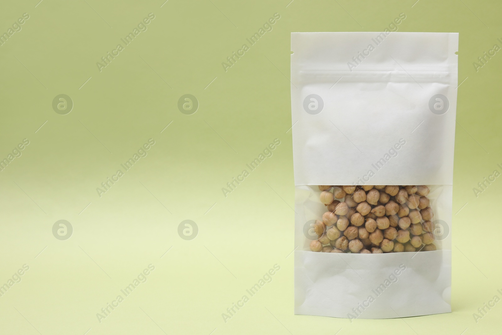 Photo of Paper pouch bag with chickpeas on light green background. Space for text