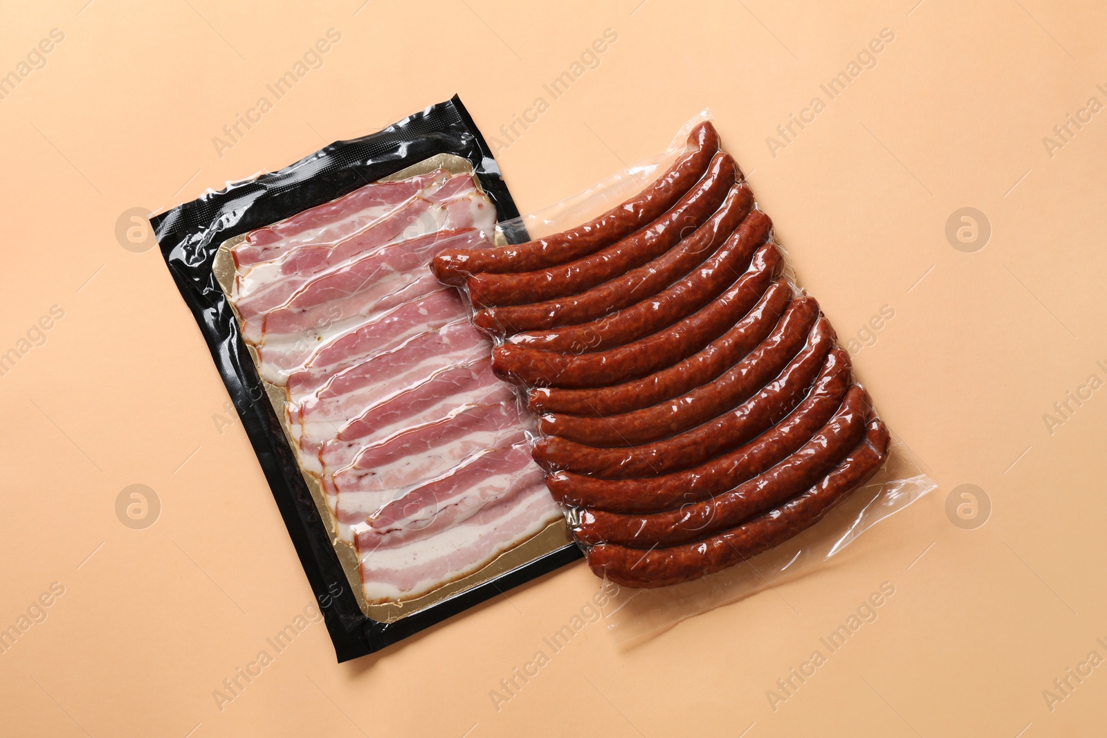 Photo of Packs of sausages and bacon on color background, top view