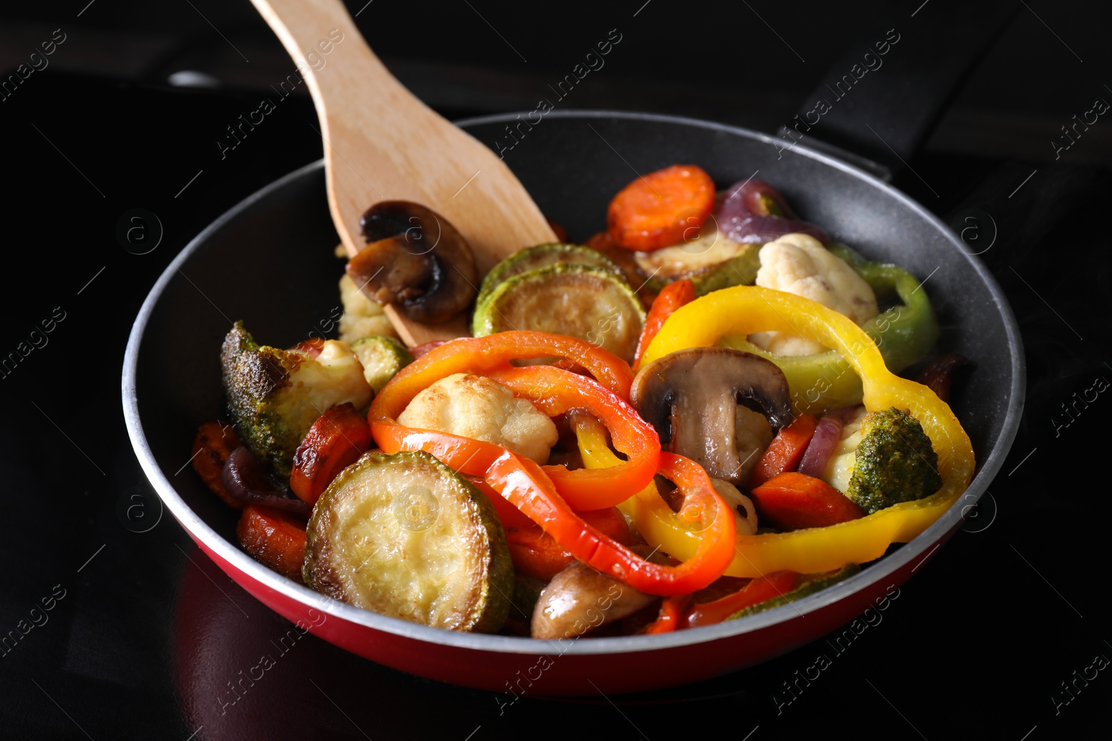 Photo of Frying pan with vegetables and mushrooms on stove, closeup