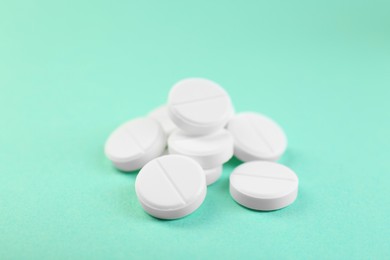 Photo of Pile of antibiotic pills on turquoise background, closeup