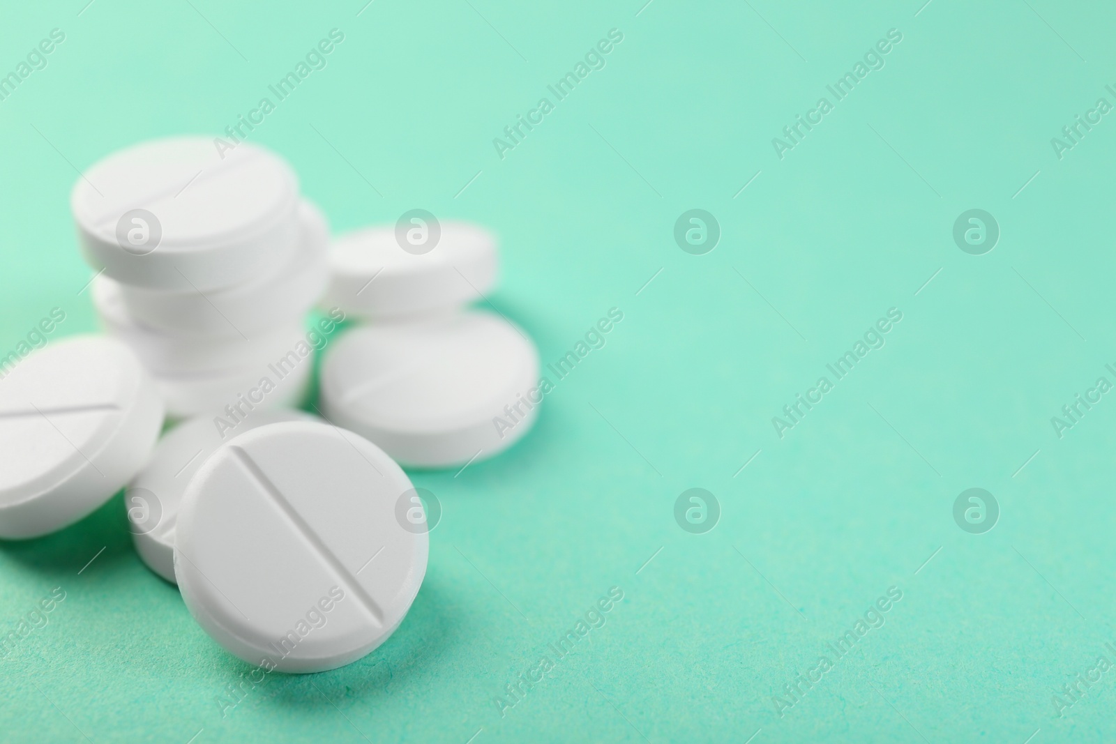 Photo of Pile of antibiotic pills on turquoise background, closeup. Space for text