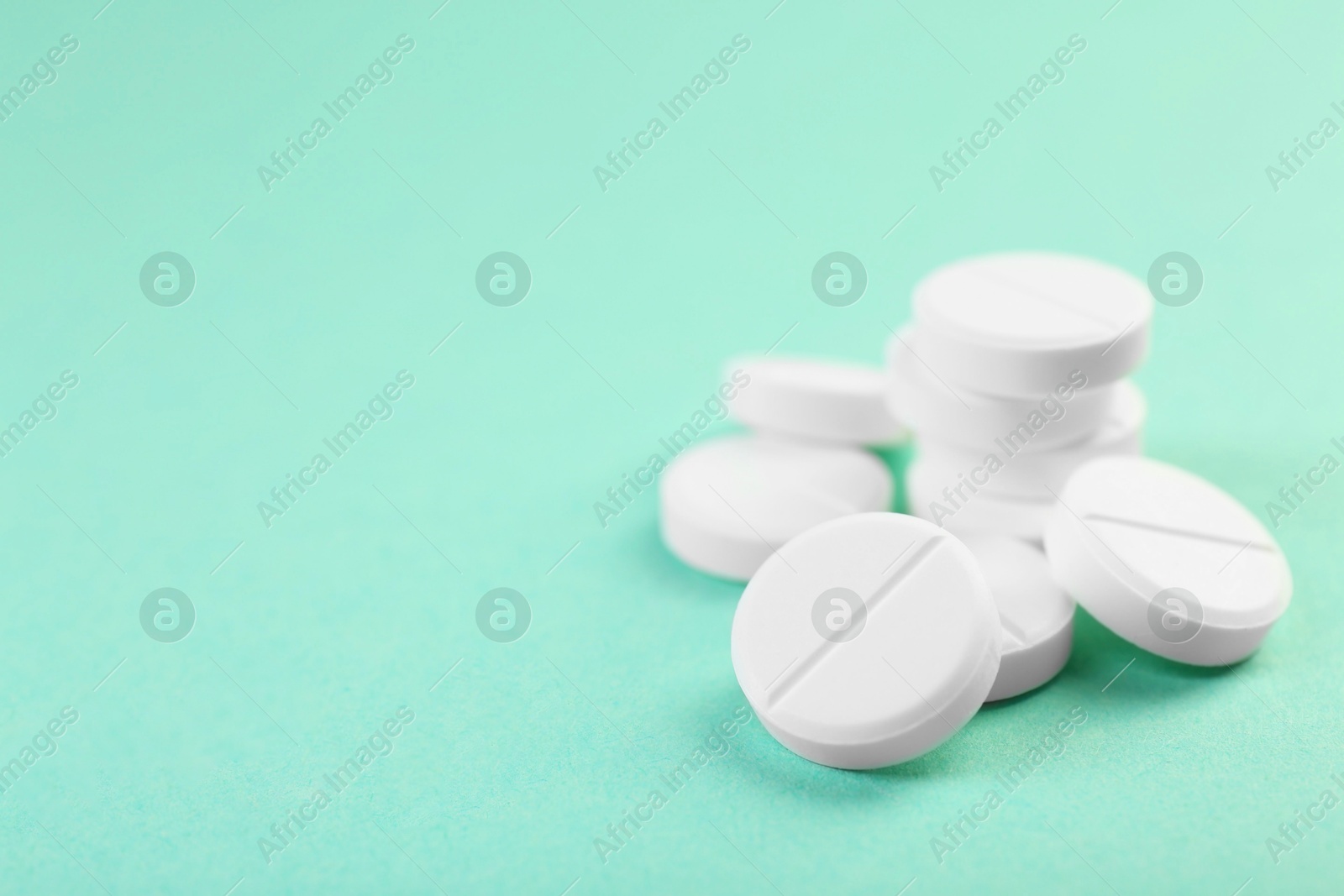 Photo of Pile of antibiotic pills on turquoise background, closeup. Space for text