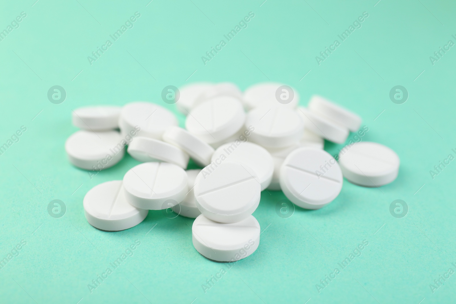 Photo of Pile of antibiotic pills on turquoise background, closeup