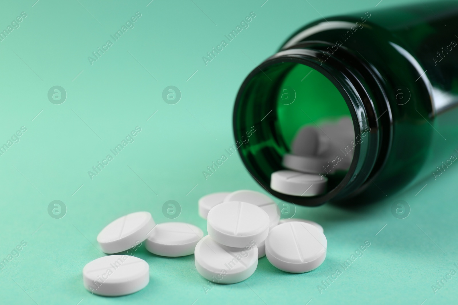 Photo of Medical bottle with antibiotic pills on turquoise background, closeup. Space for text