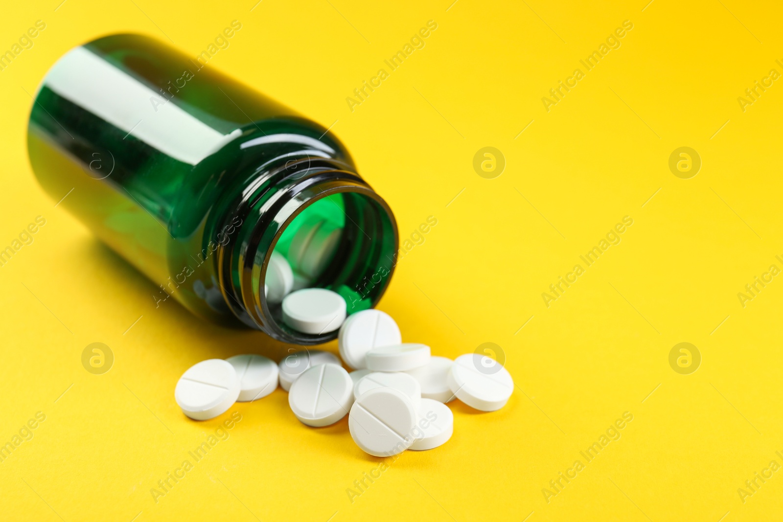 Photo of Medical bottle with antibiotic pills on yellow background, closeup. Space for text