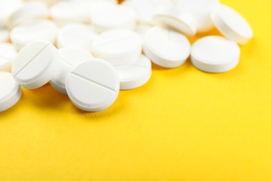 Pile of antibiotic pills on yellow background, closeup