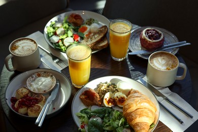 Photo of Tasty breakfast. Different meals and drinks served on wooden table in cafe