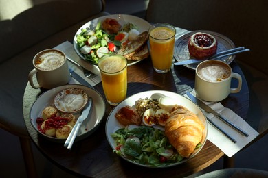 Photo of Tasty breakfast. Different meals and drinks served on wooden table in cafe