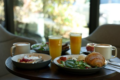 Photo of Tasty breakfast. Different meals and drinks served on wooden table in cafe